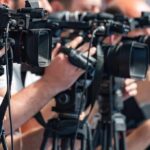 Family Handoff Sparks Senate Scramble television cameras on tripods at a media event