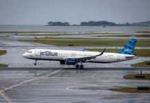 jetBlue airplane taxiing on a wet runway near the coast