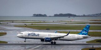 jetBlue airplane taxiing on a wet runway near the coast