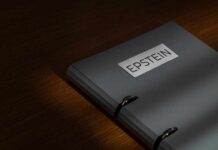 Epstein Probe Explodes: Billionaire In Contempt? A gray folder labeled 'EPSTEIN' resting on a wooden surface