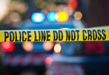 Football Boss Shot Dead At 1 A.M. Police tape and lights at crime scene.