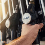 A hand holding a diesel fuel nozzle at a gas station