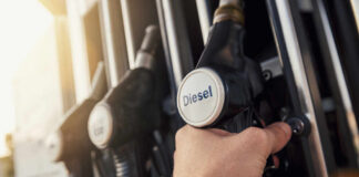 A hand holding a diesel fuel nozzle at a gas station