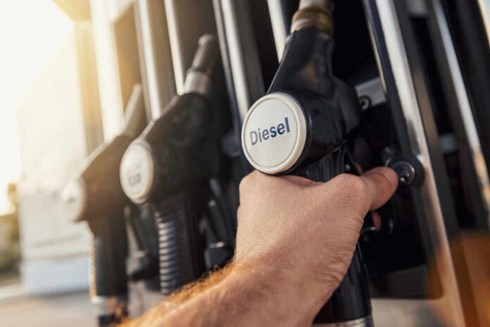 Man,Hand,Holding,Gas,Pump,Nozzle A hand holding a diesel fuel nozzle at a gas station