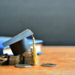 Graduation cap on top of coins to represent student loans