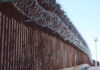 Border fence topped with coils of razor wire