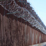 Border fence topped with coils of razor wire
