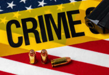 A gun and bullets on an American flag with a crime scene marker
