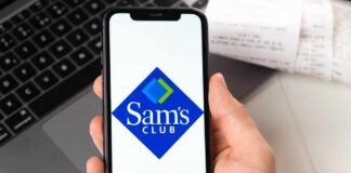A hand holding a smartphone displaying the Sam's Club logo