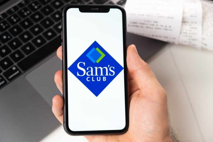 A hand holding a smartphone displaying the Sam's Club logo