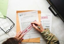 A person in military attire marking a classified document with a red 'FOR SECRET' stamp