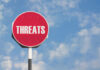 Trump Threat Jolts Authorities Red sign with the word threats against sky