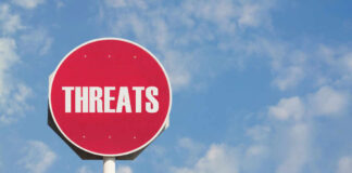 Red sign with the word threats against sky