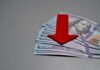 Protest Café Drowns In Debt Red downward arrow on stack of US hundred-dollar bills