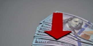 Red downward arrow on stack of US hundred-dollar bills