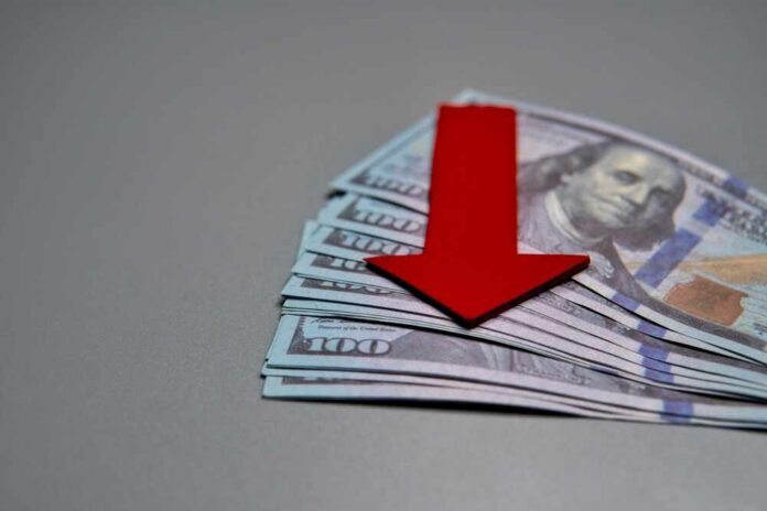 A,Red,Arrow,Pointing,Downwards,On,Top,Of,A,Pile Red downward arrow on stack of US hundred-dollar bills