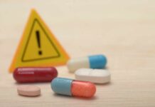 Pills with warning sign in background