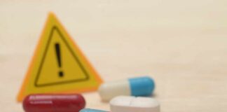 Pills with warning sign in background