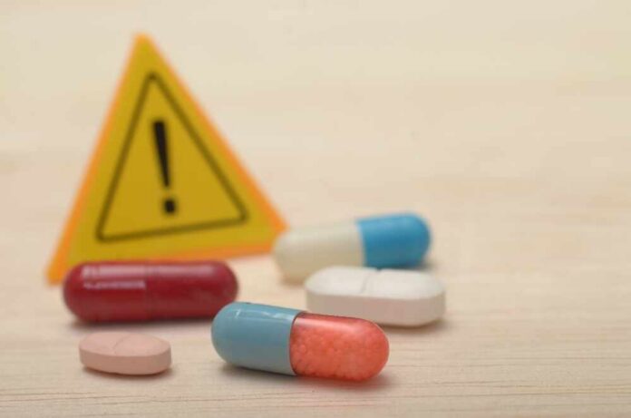 The,Danger,Of,Drug,Abuse:,Warning,Signs,And,Pill,Capsules Pills with warning sign in background