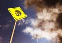 Double Death Hits School Yellow warning sign with skull symbol under dramatic cloudy sky