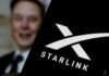 Elon Musk behind a phone showing the Starlink logo