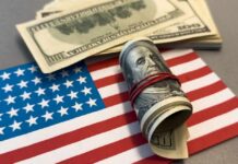 Huge GOP Money Shockwave A roll of hundred dollar bills placed on an American flag