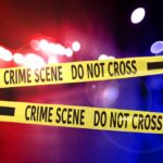 Crime scene tape with police lights in the background