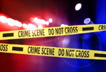 Crime scene tape with police lights in the background