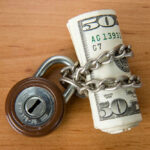 Rolled US dollars wrapped in chain with a padlock