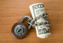 Rolled US dollars wrapped in chain with a padlock