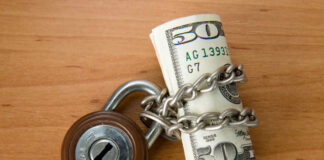 Rolled US dollars wrapped in chain with a padlock