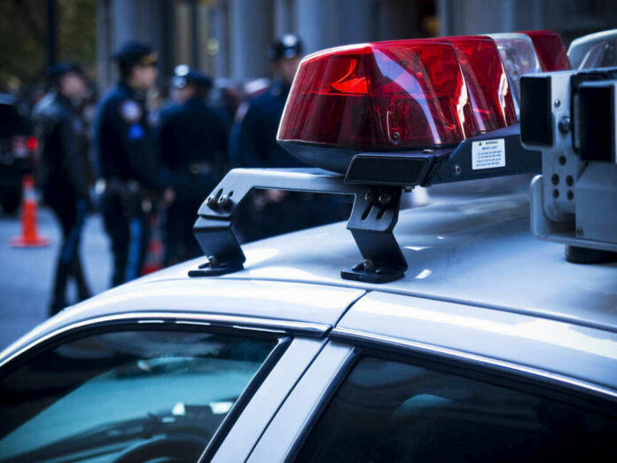 Police car lights with officers blurred in background.